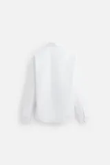 Camisa celeste de algodón, corte regular fit, con cuello italiano, manga larga con puños abotonados y cierre frontal con botones.
