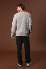 Sweater verde oliva de punto trenzado con cuello redondo y mangas largas.