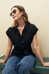 Camisa negra con broderie, de manga corta, calce relajado, cuello clásico, abotonada al frente y con lazo regulable en la cintura.
