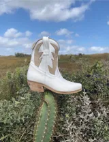 Botas cortas negras de cuero con bordados blancos estilo cowboy.