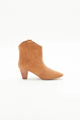 Bota corta de gamuza color camel, estilo cowboy, con taco medio de madera y recortes grabados en forma de mariposa en los laterales.