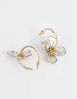 Aros argolla dorados con dije de flor plateada y centro dorado.