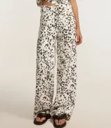 Pantalón wide leg de sarga con estampado animal print dálmata, trabillas en la cintura, cierre con botón y cremallera, y bolsillos delanteros y traseros.