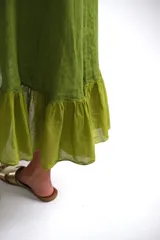 Vestido verde pistacho de lino italiano, corte suelto, sin mangas, con escote redondo y ruedo asimétrico con volados.