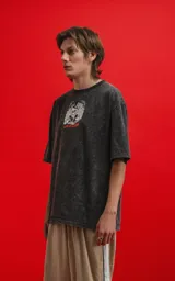 Remera oversize de algodón premium, color gris oscuro con efecto nevado (acid wash), con estampa frontal de calaveras inspiradas en Disney y texto "CHILLED BY BONE".