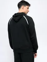 Canguro de felpa color crema con capucha, cordones y logo Umbro bordado en rojo. Presenta ribete rojo en hombros y bolsillo tipo canguro con cierre lateral.