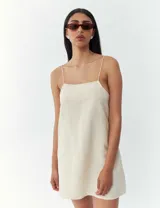 Vestido corto color crema con breteles finos y corte recto.
