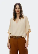 Blusa color crema con escote en V y mangas cortas amplias.