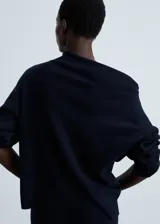 Sweater de punto azul marino con cuello alto asimétrico envolvente y manga larga.