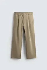 Pantalón de hombre color beige, de corte relajado y pierna ancha, con cintura elástica fruncida y pliegues frontales.