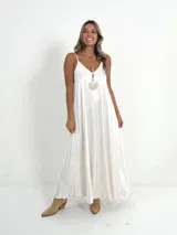Vestido largo blanco de tela nacarada, con escote en V y tirantes finos.
