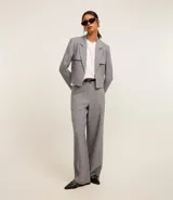 Blazer corto gris de poliéster y elastano, con solapas en el escote y cierre con gancho. Presenta bolsillos delanteros y corte horizontal en la espalda.