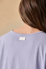 Remera blanca de algodón con estampado de un tucán, palmeras y la frase 'Tropical Bliss' en tonos naranja y rosa.