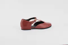 Zapato flat de cuero con estampado de vaca en blanco y negro, con tira delantera y hebilla lateral.