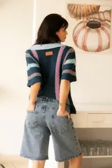 Camisa tejida de algodón a rayas verticales en tonos azul, celeste y rosa, con botones al frente y mangas cortas.