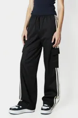 Pantalón negro de corte ancho con cintura elastizada y cordón ajustable. Presenta una franja vertical blanca a lo largo de la pierna y un bolsillo tipo cargo en el muslo.