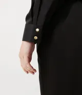 Blusa de satén negra con escote cruzado, manga larga y elástico en la cintura.