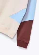 Polerón color beige con mangas celeste y marrón, y logo de corazón rosa en el pecho.