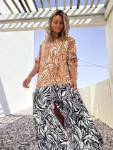 Vestido camisero largo con estampado de hojas en tonos marrones y blancos en la parte superior, y estampado de cebra en blanco y negro en la parte inferior.