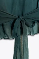 Top verde esmeralda con cuello halter, volantes escalonados y espalda descubierta con lazo.