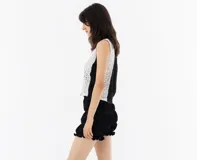 Top blanco de encaje con base de tela suave, sin mangas y cuello redondo.