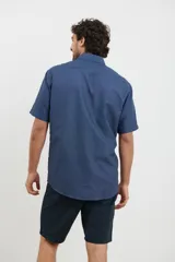 Camisa de manga corta azul con estampado de lunares blancos, cuello button-down y bolsillo en el pecho.