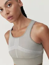 Top deportivo color gris con líneas decorativas blancas, de sujeción alta y copas extraíbles.