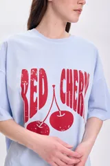 Remera celeste de corte amplio con estampado de cerezas rojas y texto "Red Cherry".