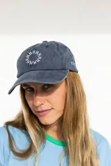 Gorra marrón de algodón con visera curva y bordado frontal con la palabra "HAHA" repetida en círculo.
