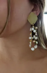 Aros colgantes con base de rombo dorado y diseño irregular de perlas blancas, beige y doradas.