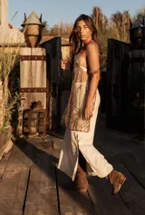 Top dorado brillante con tela bordada con canutillos dorados y detalles en cuero rojo. Se ajusta en cuello y espalda.