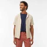 Camisa de manga corta color crema con rayas verticales marrones, cuello cubano y cierre frontal con botones.