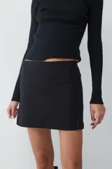 Minifalda negra de tiro medio, confeccionada en tejido crepé con silueta recta y diseño minimalista.