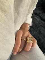 Anillo dorado con diseño de bandas entrelazadas con textura irregular.