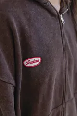 Campera con capucha color marrón con cierre frontal y logo de la marca en el pecho.