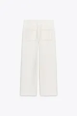 Pantalón de tiro alto color blanco, confeccionado en hilatura con viscosa, con bolsillos laterales y de plastrón en espalda. Detalle de costura marcada en delantero e hilo a contraste. Cierre frontal con cremallera, botón interior y gancho metálico.