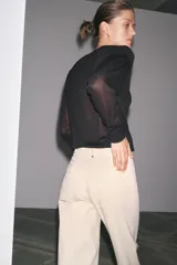 Jeans de tiro alto, pierna ancha y largo al tobillo, en denim celeste claro con efecto lavado. Presenta costura marcada en el centro de cada pierna y cierre frontal con cremallera y botón.