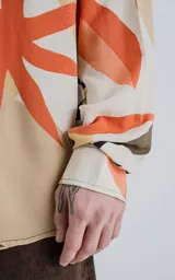 Camisa de manga larga con estampado de hojas en tonos beige, naranja, negro y verde.