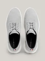 Zapatillas de corte medio color gris claro, con exterior de ante, interior de poliéster reciclado, plantilla extraíble de poliuretano y poliuretano reciclado, suela de goma y caucho, trabilla para calzar distintiva y logo de Tommy Hilfiger en bajo relieve en el lateral y la parte trasera.
