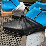 Zueco de cuero negro con punta cuadrada y detalle de nudo en el empeine.