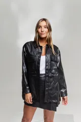 Chaqueta negra simil cuero con cuello camisero, cierre frontal con botones a presión, bolsillos con solapa en el pecho y corte recto.