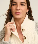 Cardigan de punto color crema con diseño trenzado en el frente, cuello alto, cierre abotonado y mangas largas grises.