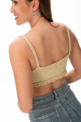 Top crop tejido al crochet color dorado, con breteles finos y terminación con flecos.