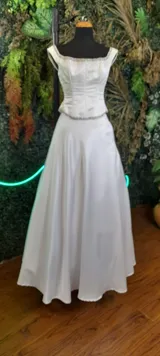 Vestido en satén blanco con top armado y bordado de canutillos en plata, acompañado de una falda con movimiento.