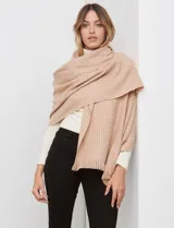 Bufandón tejido de poliéster, color beige claro con un patrón de micro-tejido en tonos rosados y naranjas. Presenta flecos en los bordes.