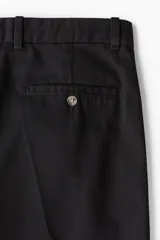 Pantalón de vestir negro con pliegues, corte recto y bolsillos laterales.