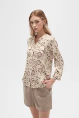 Camisa de viscosa con estampado floral en tonos azul, beige y blanco. Tiene cuello mao, mangas largas y bolsillos en el pecho.
