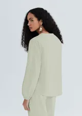 Blusa verde claro a rayas verticales, con cuello en V y cierre frontal con botones. Mangas 3/4 abullonadas y corte holgado.