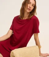 Vestido corto marrón, estilo camiseta, con escote redondo, mangas cortas y bolsillos laterales. El bajo es redondeado.