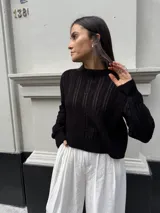 Sweater tejido negro con diseño en ochos y cuello redondo.